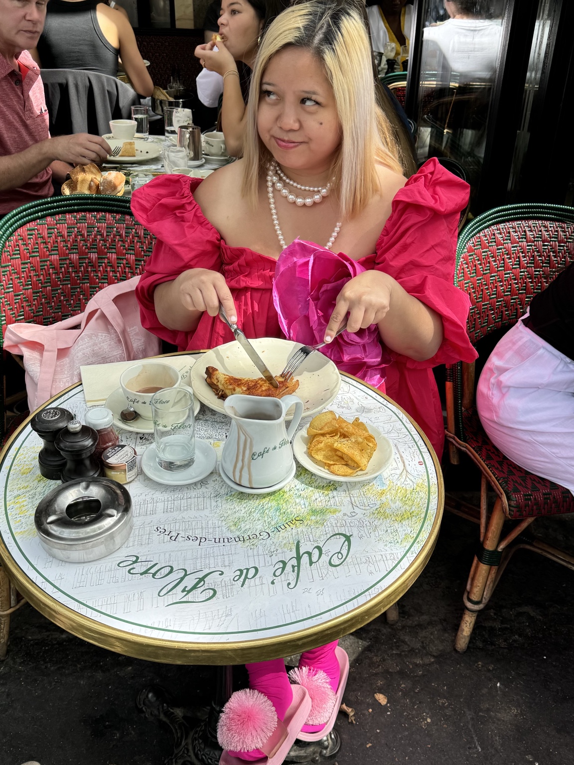 Dee in a bright pink dress enjoying a meal at Café de Flore in Paris
